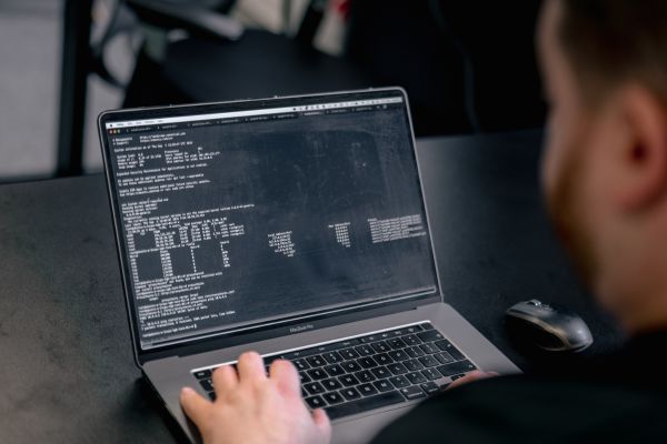 Penetration tester reviewing code to identify file upload vulnerabilities on laptop