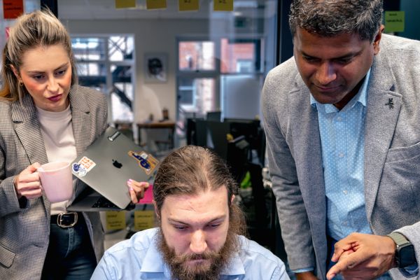 Team of three cyber security experts discussing June 2024 cyber attack trends on laptop