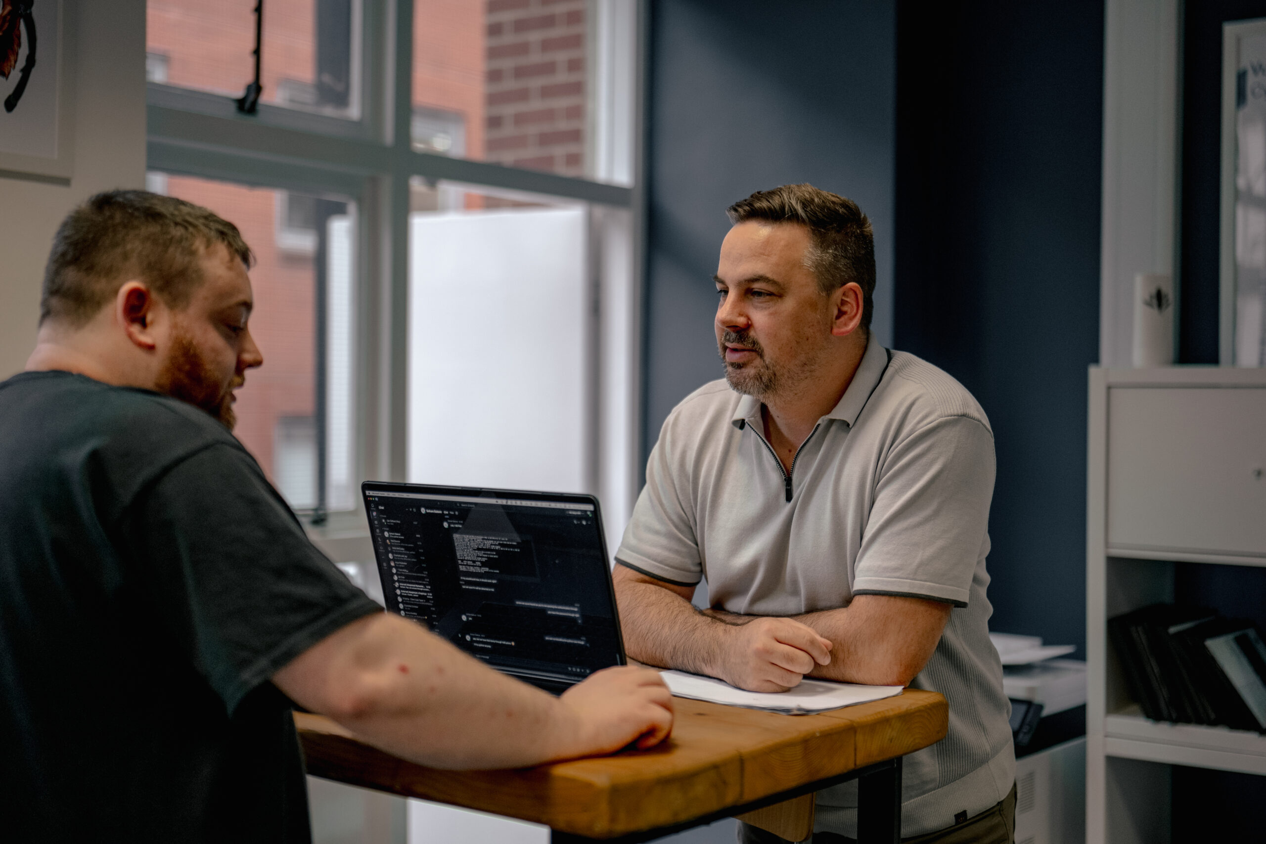 Cybersecurity experts conversing about code review details on their laptops