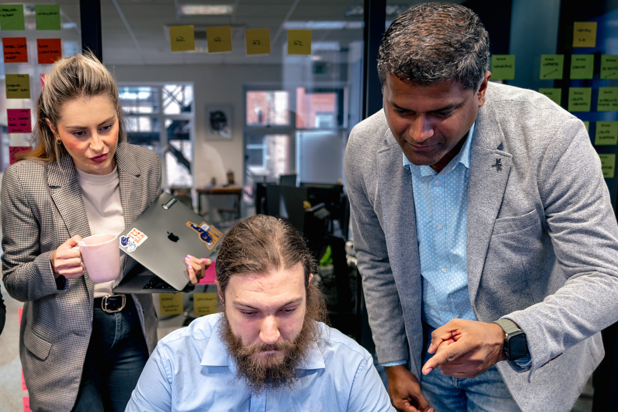 CTO, analyst, and client manager reviewing ISO 42001 certification details on laptop